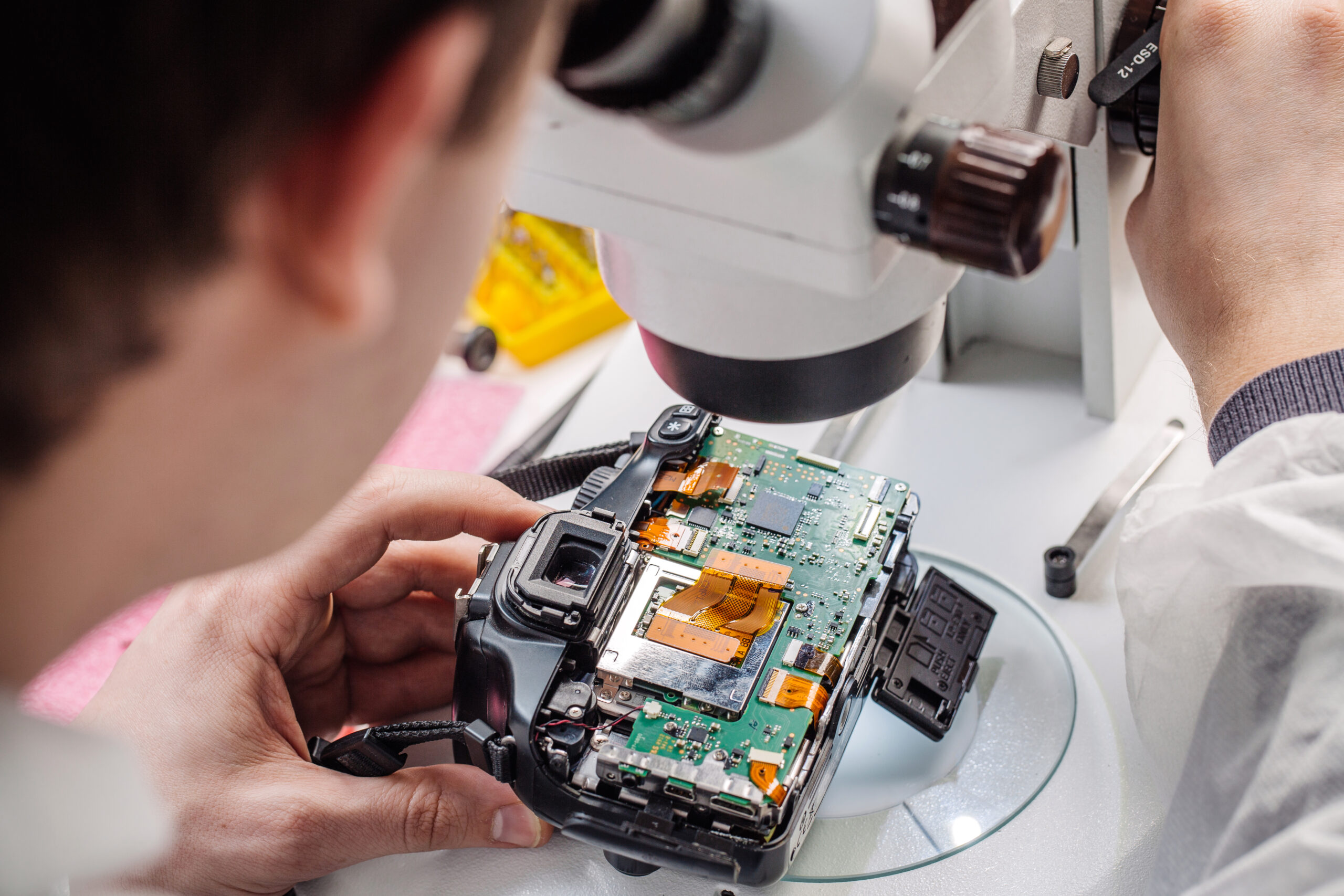 Close up hands of a service worker repairing digital camera.